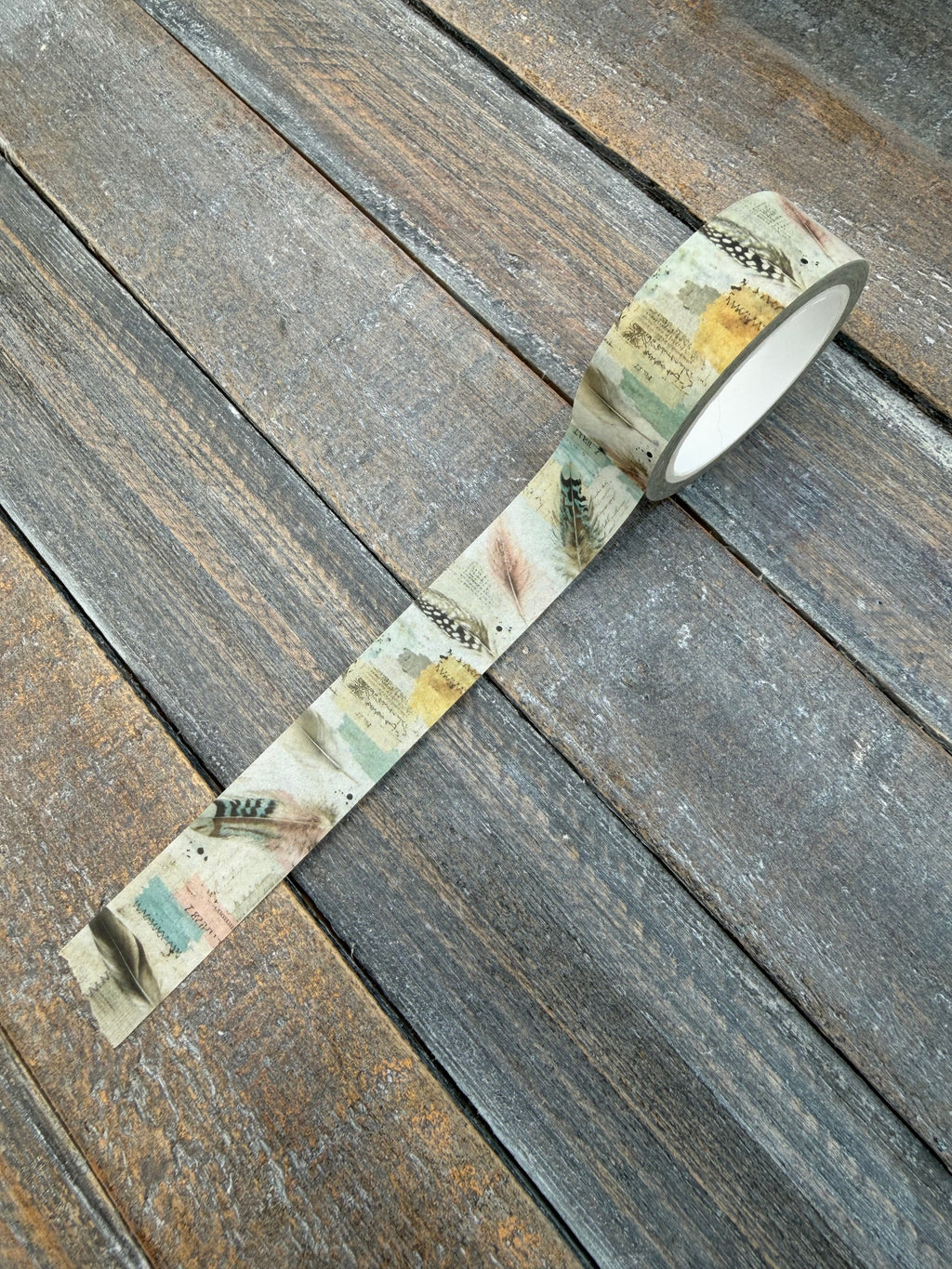 Feather Your Nest washi tape unrolled showing speckled feathers and handwritten scraps